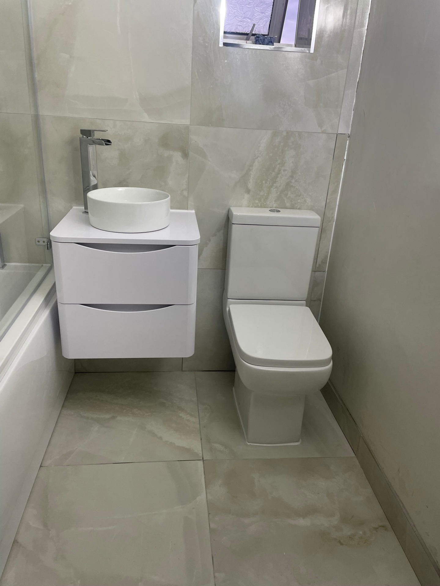 Contemporary bathroom with wall-hung vanity, counter-top basin and onyx-effect large format tiles