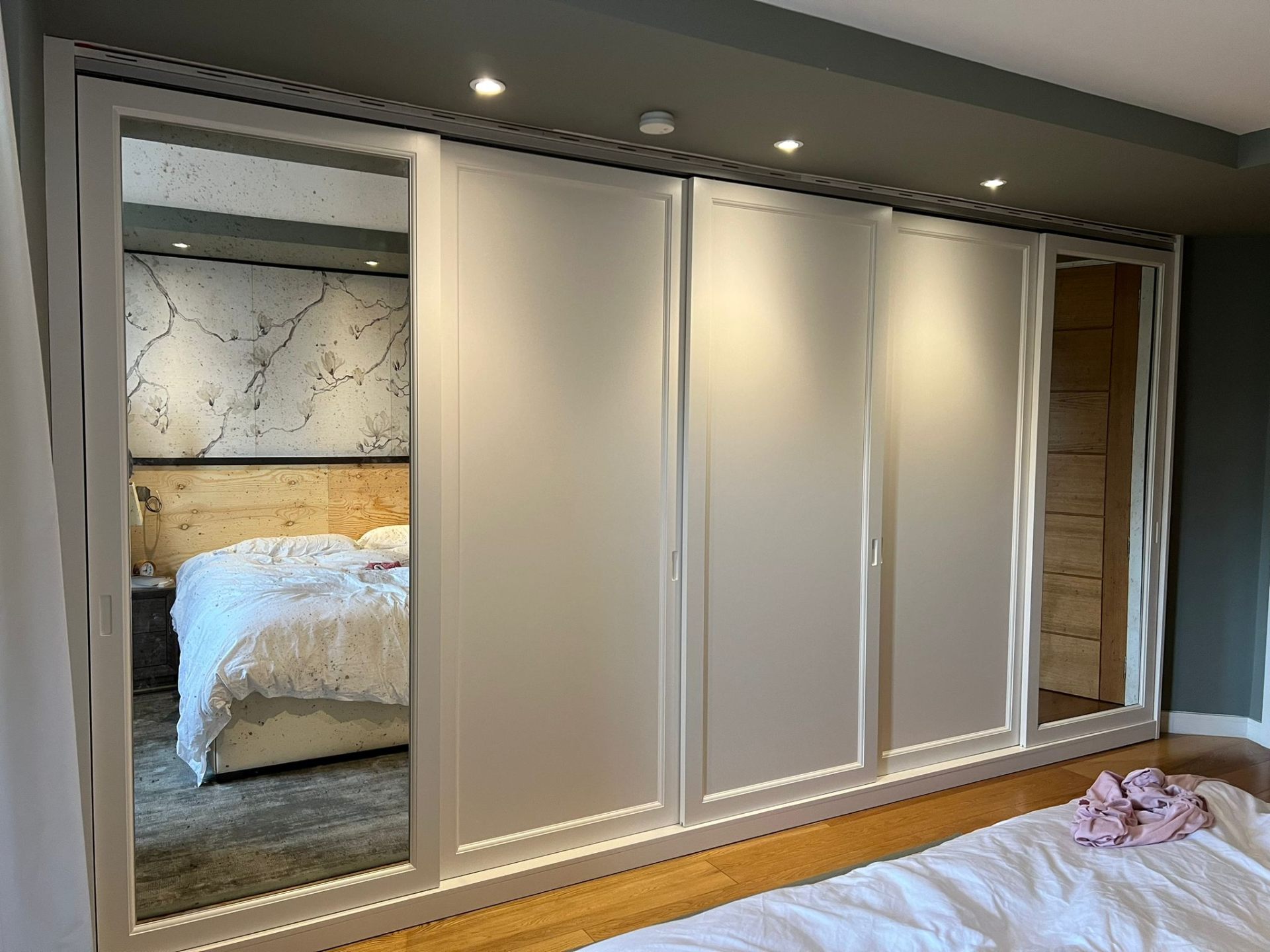 Large fitted sliding wardrobe with three white panels and two mirrored outer doors in a bedroom — Ash Villa bespoke joinery, West London