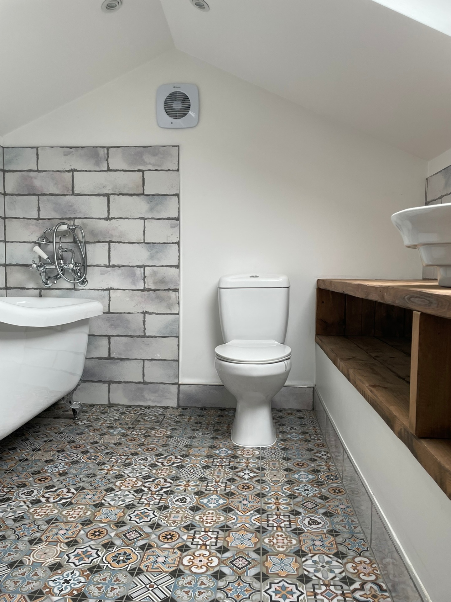 Loft bathroom with cast-iron roll-top bath, exposed traditional shower and patterned encaustic floor tiles, Acton refurbishment