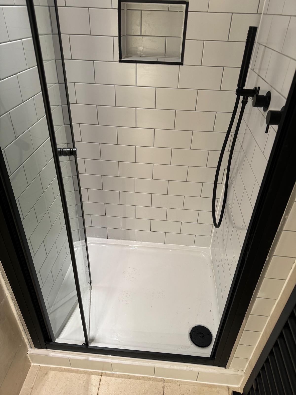 Walk-in shower with black-framed glass, white metro tiles with dark grout and a recessed niche — Ash Villa bathroom installation